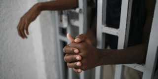 Barns händer sträcks ut genom gallret i en fängelsecell.