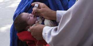 En bebis får en dos poliovaccin i munnen.