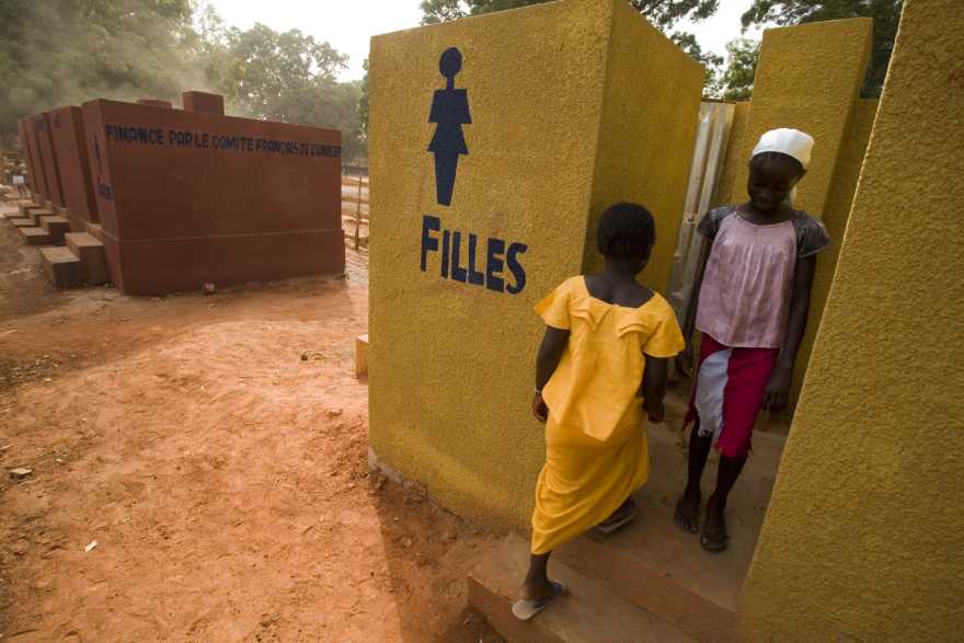 Två flickor utanför en toalett för flickor, i Senegal.